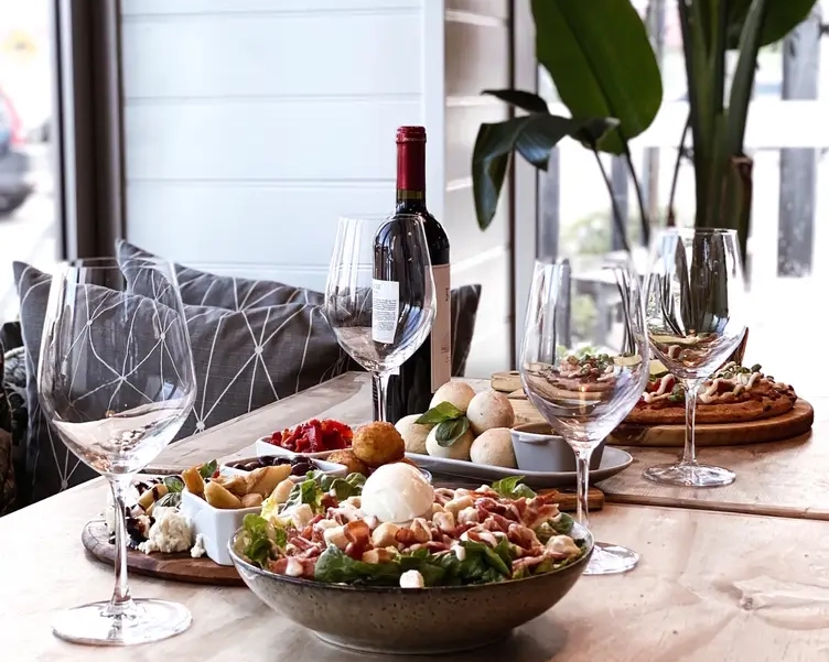 A dining table set with various dishes, wine, and glasses in a restaurant setting.