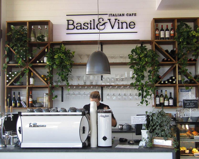 Interior view of Basil & Vine Italian Cafe featuring a coffee machine and decorative plants.